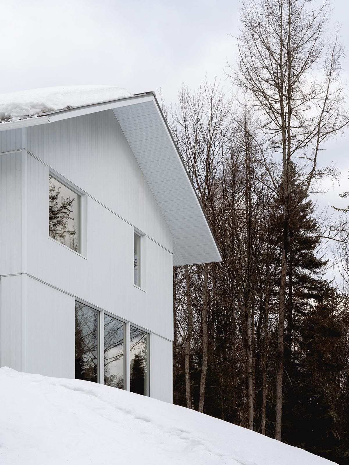 Canadian winter home designed by Atelier L'Abri looks like it is covered in  snow in the forest