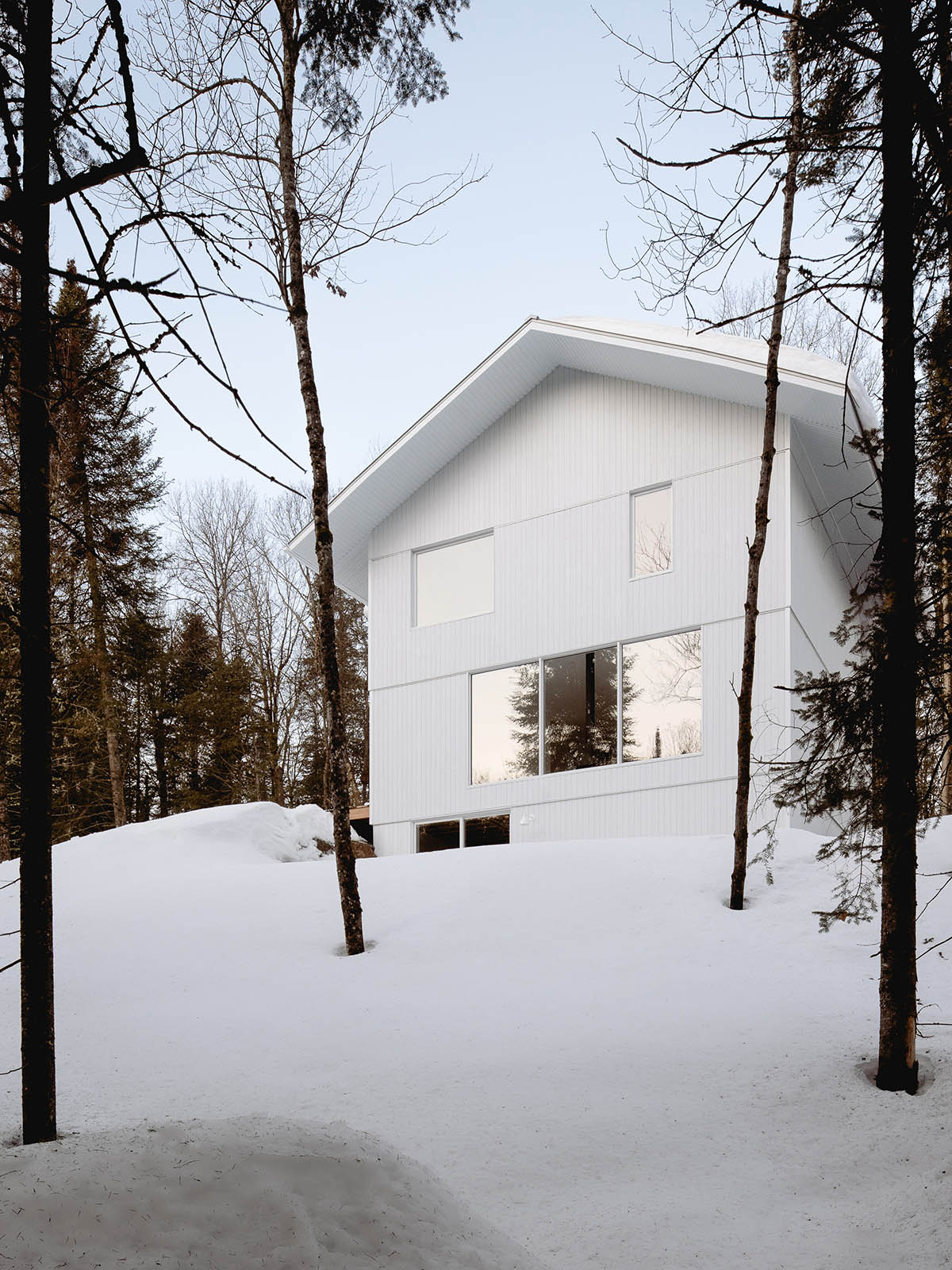 Canadian winter home designed by Atelier L'Abri looks like it is covered in  snow in the forest