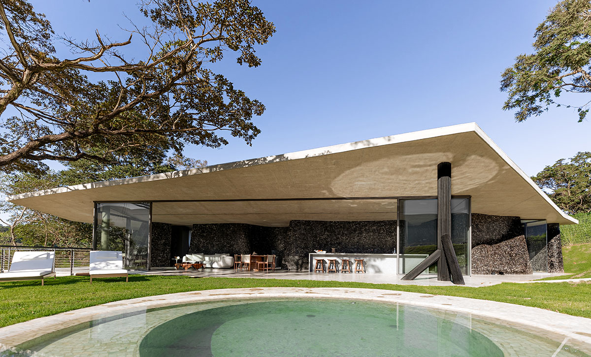 Seriema House is shaped around massive, black Portuguese stones for contemplation in Brazil