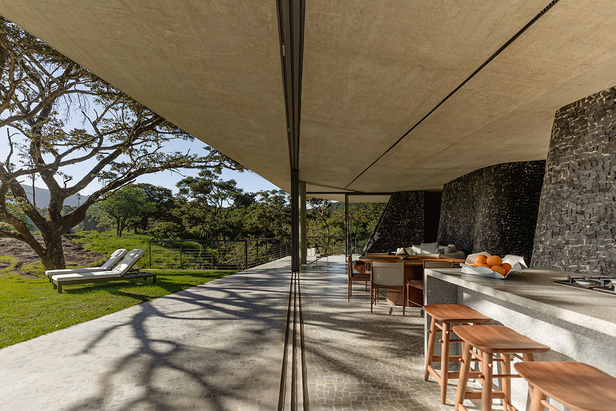 Seriema House is shaped around massive, black Portuguese stones for contemplation in Brazil