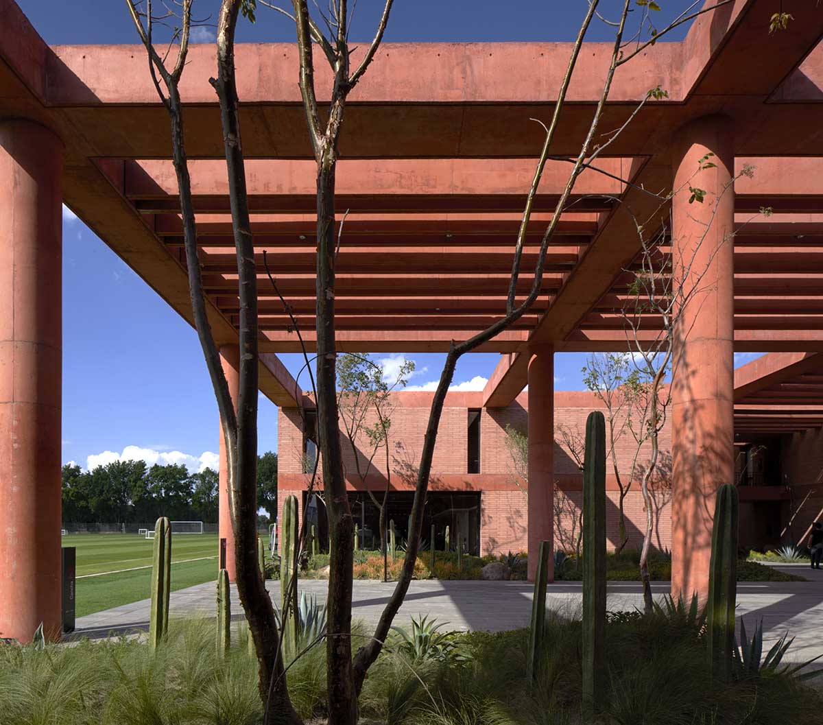 Red pigmented gridded structure defines village-like Mexican sport facility by Sordo Madaleno