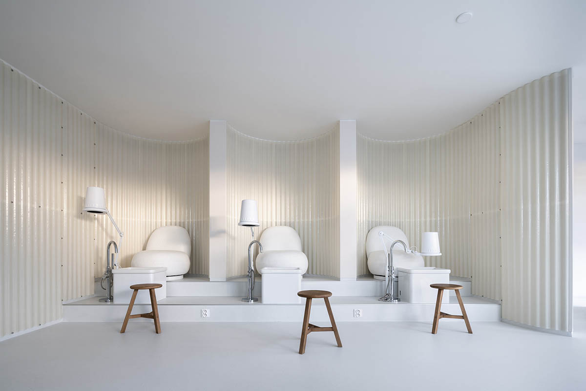 A beauty salon brings warm light with translucent partitions and tactile elements in Prague