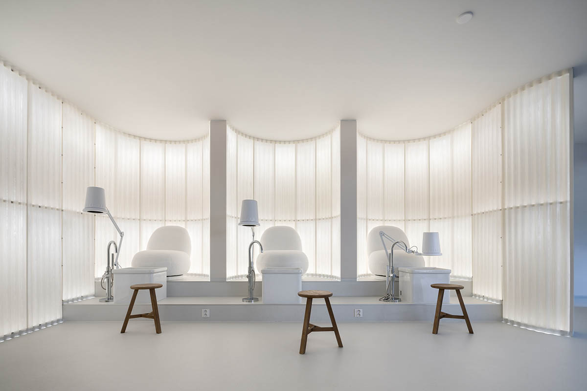 A beauty salon brings warm light with translucent partitions and tactile elements in Prague