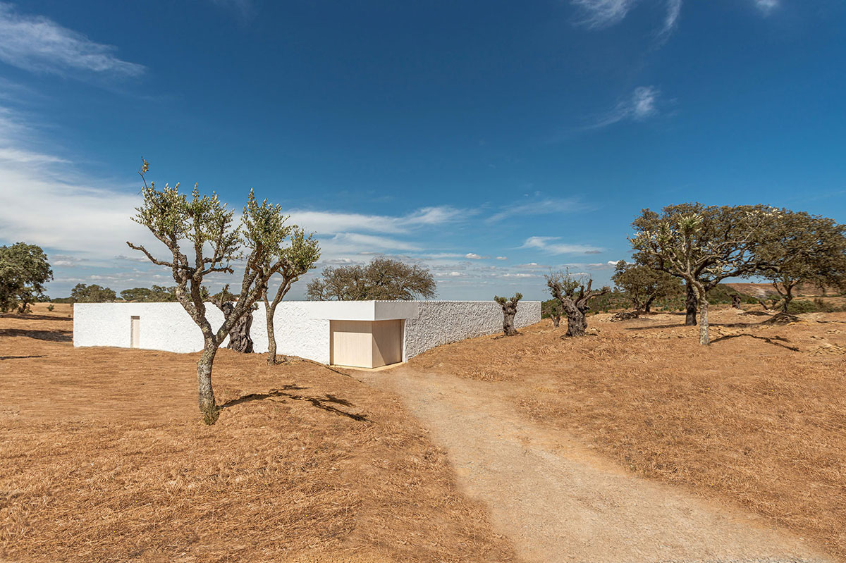 Low-profiled whitewashed stone walls wrap living units of Casa da Volta by PROMONTORIO and João Cravo