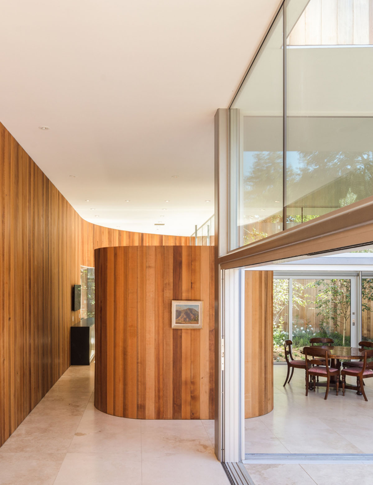 Curving wooden walls form Roofless House among trees in Atherton