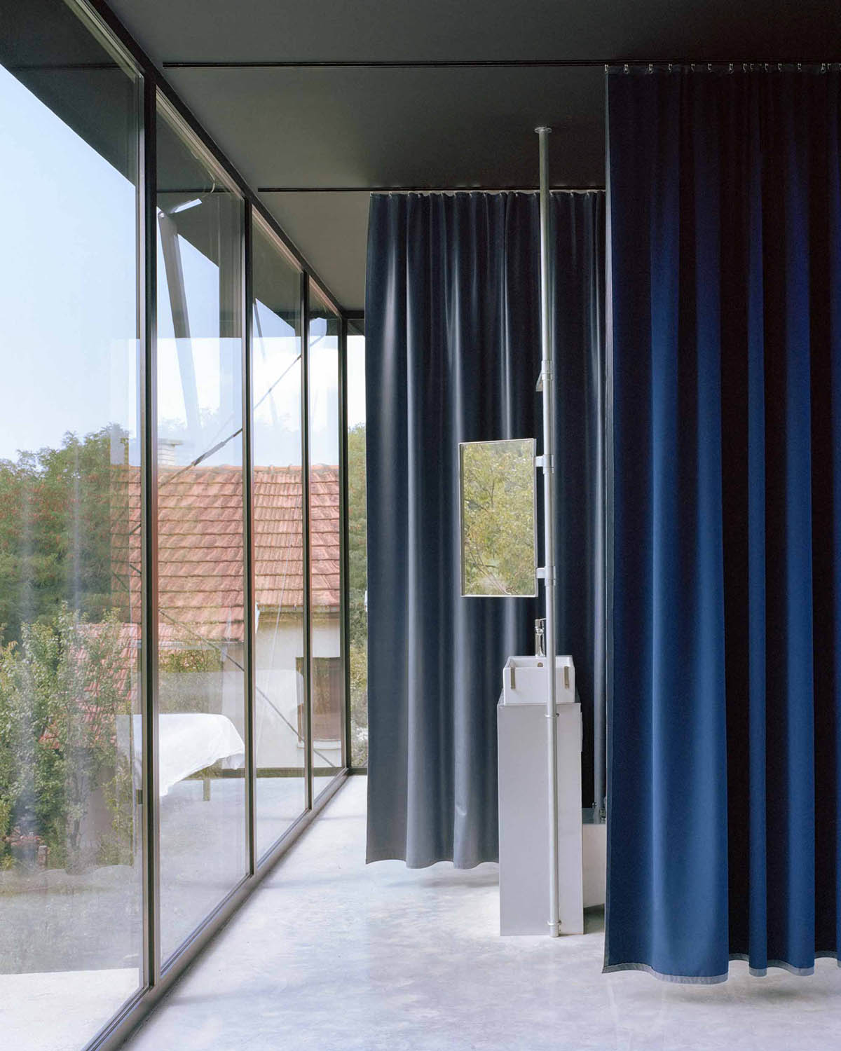 Avala House by TEN is a fully-glazed house supported by slope and triangular column in Belgrade