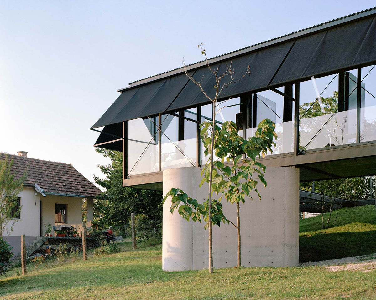 Avala House by TEN is a fully-glazed house supported by slope and triangular column in Belgrade