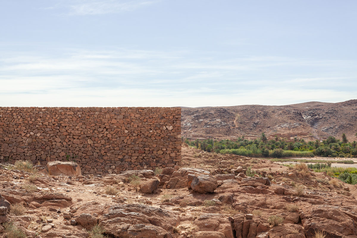 Two elongated walls made of granite rocks and earth form this women's house in a village of Morocco