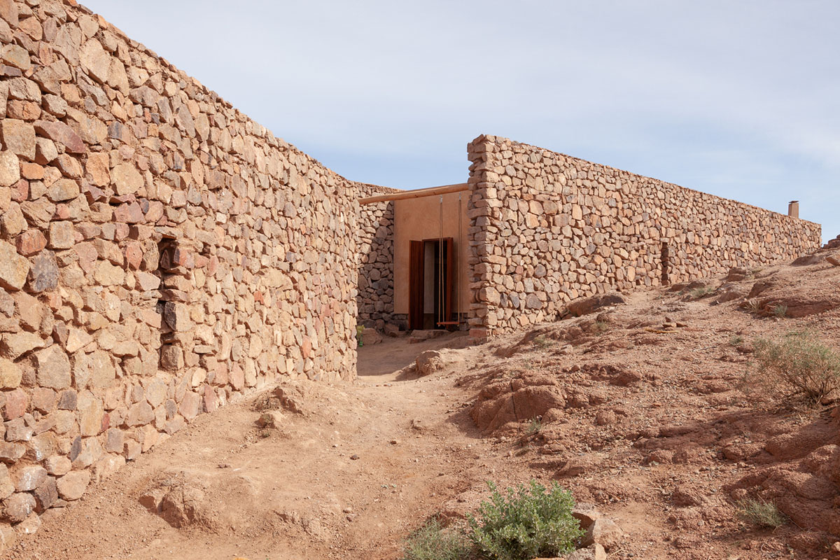 Two elongated walls made of granite rocks and earth form this women's house in a village of Morocco