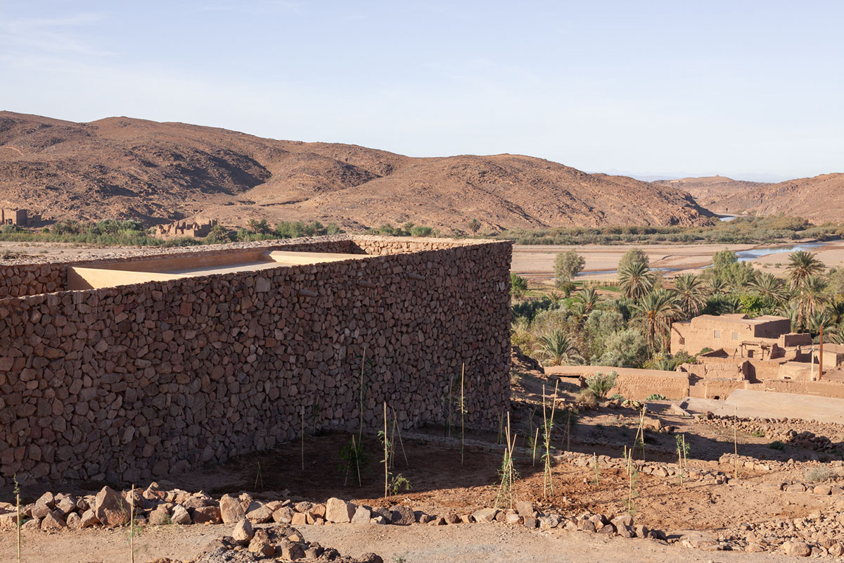 Two elongated walls made of granite rocks and earth form this women's house in a village of Morocco