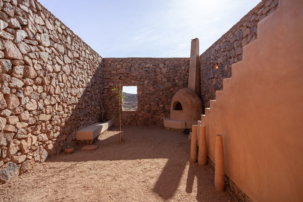 Two elongated walls made of granite rocks and earth form this women's house in a village of Morocco