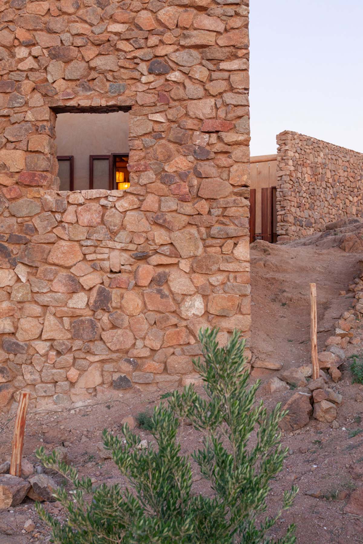 Two elongated walls made of granite rocks and earth form this women's house in a village of Morocco