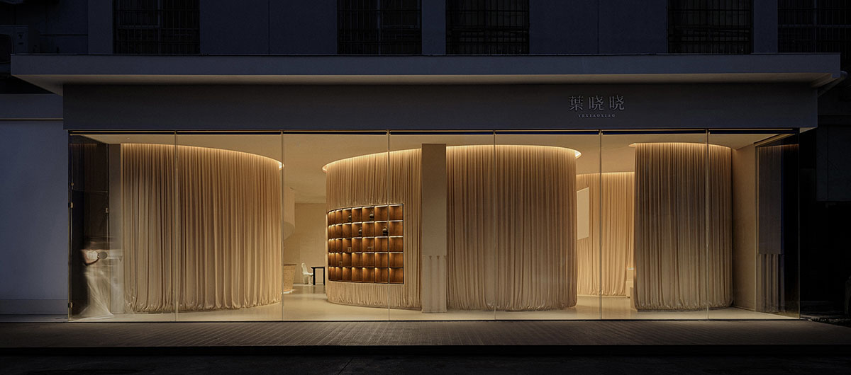 Tea house interiors wrapped by earth-toned fabric curtains act like 