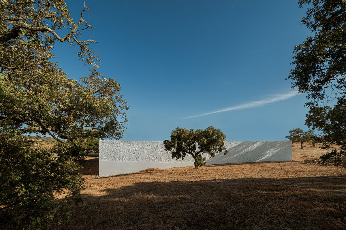 Low-profiled whitewashed stone walls wrap living units of Casa da Volta by PROMONTORIO and João Cravo